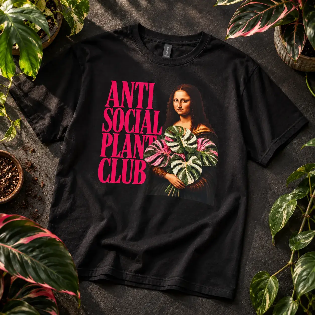 Black tee: Anti Social Plant Club in pink next to the Mona Lisa holding a variegated monstera