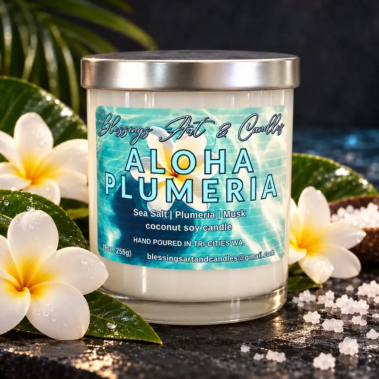 Aloha Plumeria candle with a turquoise water label, next to plumeria flowers