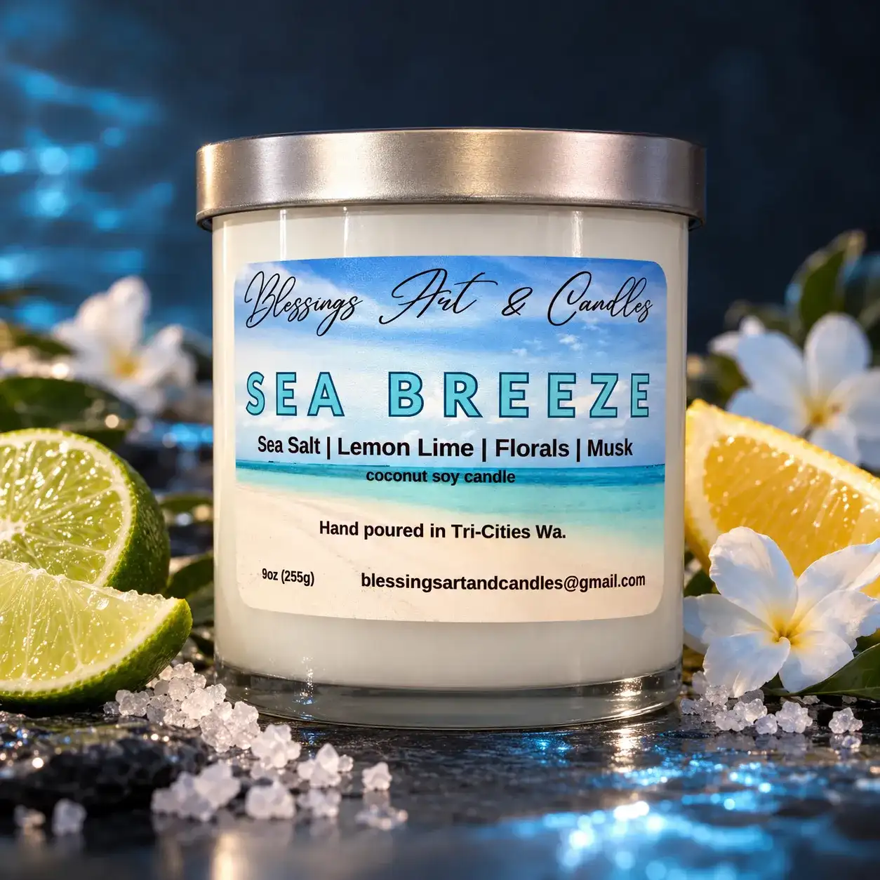 Sea Breeze candle with a blue ocean label, next to limes, a lemon and white flowers