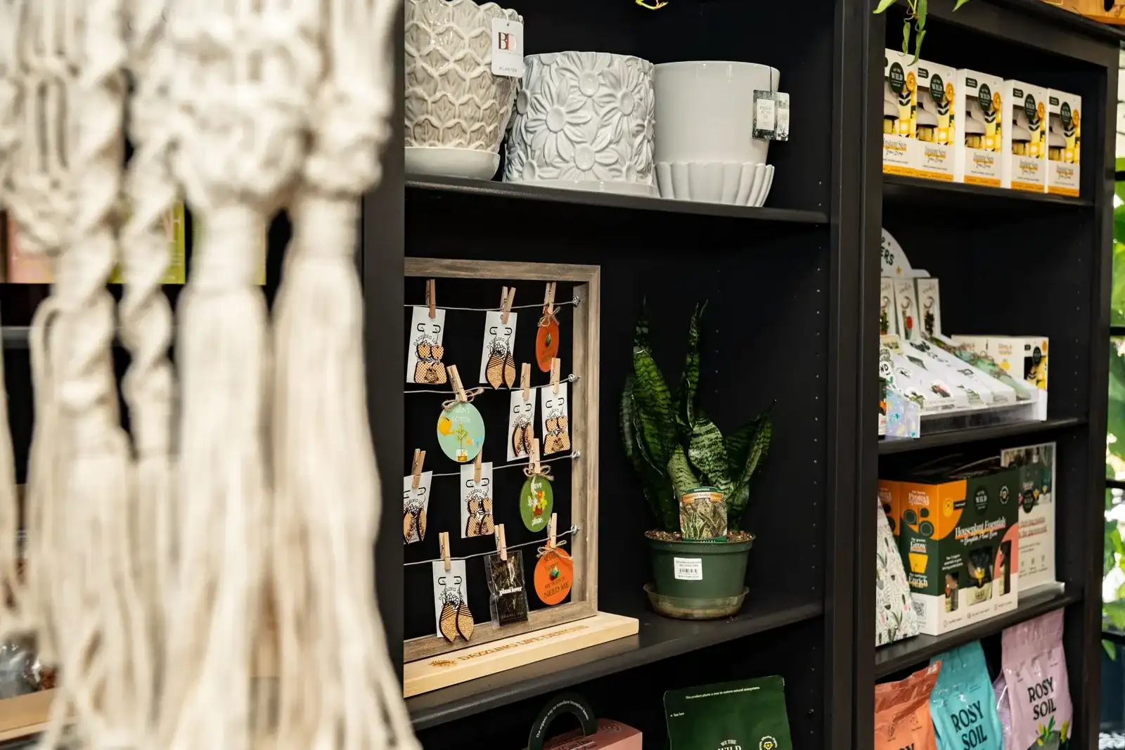 Black shelves with macrame, handmade cards, pots and gifts